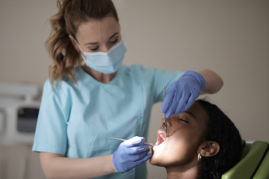 femme dentiste avec des instrument étant en train de soigner une patiente - ares dental